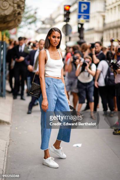 Model Cindy Bruna wears a white tank top, cropped blue jeans, white sneakers shoes , outside Elie Saab, during Paris Fashion Week Haute Couture Fall...