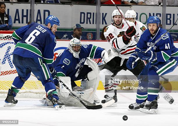 Andrew Alberts and Sami Salo of the Vancouver Canucks and Troy Brouwer of the Chicago Blackhawks look for a rebound in front of Roberto Luongo of the...