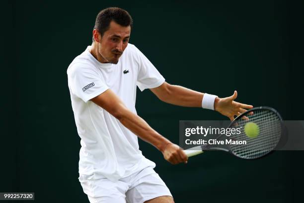 Bernard Tomic of Australia returns a shot against Kei Nishikori of Japan during their Men's Singles second round match on day four of the Wimbledon...