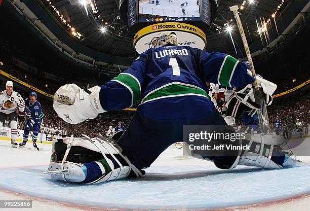 Alex Burrows of the Vancouver Canucks and Jonathan Toews of the Chicago Blackhawks look on as Roberto Luongo of the Vancouver Canucks makes a save in...