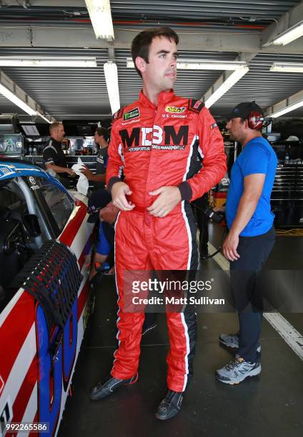 Timmy Hill, driver of the CrashClaimsR.Us Toyota, gets into his car during practice for the NASCAR Xfinity Series Coca-Cola Firecracker 250 at...
