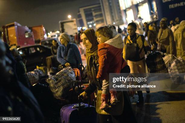 Migrants wait to board a bus at the port of Piraeus in Athens after their arrival with the 'Blue Star 2' passenger ship from the island of Lesbos, on...