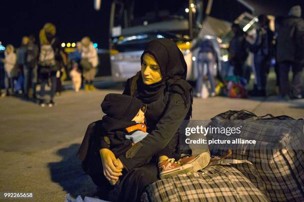 Woman refugee from Syria holds her baby as she waits to board a bus at the port of Piraeus in Athens after after her arrival with the 'Blue Star 2'...