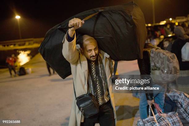 Migrant carries a bag as he arrives aboard the passenger ferry Blue Star 2 from the island of Lesbos at the port of Piraeus, near Athens on November...