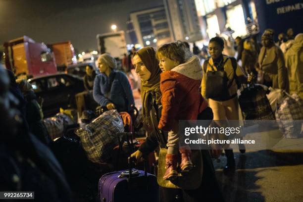 Migrants wait to board a bus at the port of Piraeus in Athens after their arrival with the 'Blue Star 2' passenger ship from the island of Lesbos, on...