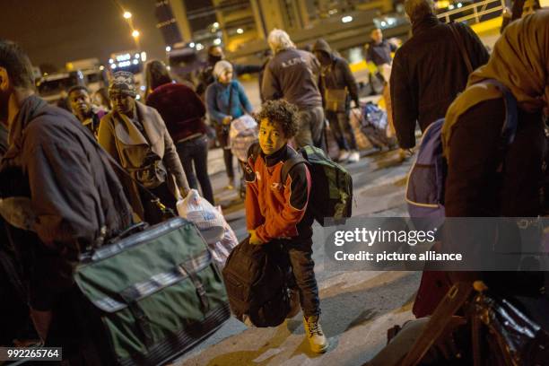 Migrants wait to board a bus at the port of Piraeus in Athens after their arrival with the 'Blue Star 2' passenger ship from the island of Lesbos, on...