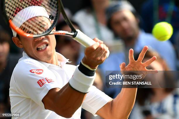 Japan's Kei Nishikori returns against Australia's Bernard Tomic during their men's singles second round match on the fourth day of the 2018 Wimbledon...