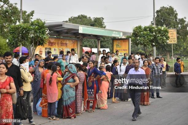 People wait to catch bus for Badarpur outside Central Secratariat Metro station after temporary shutdown of Delhi Metro's Violet Line, on July 5,...