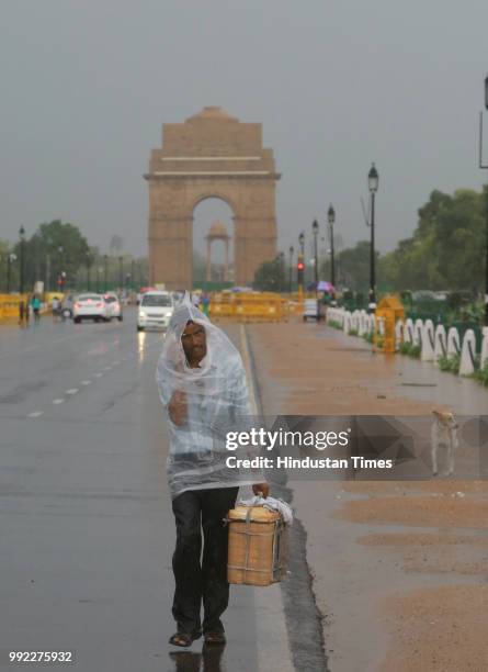 Man covers himself with plastic amid monsoon rain accompanied by strong winds at Rajpath on July 5, 2018 in New Delhi, India.