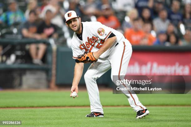 Darren O'Day of the Baltimore Orioles fields a bunted ball during a baseball game against the Seattle Mariners at Oriole Park at Camden Yards on June...