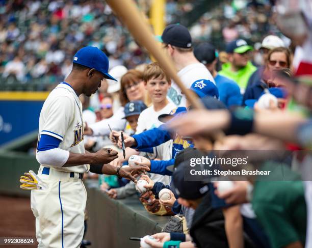 Dee Gordon of the Seattle Mariners signs autographs for fans before a game against the Kansas City Royals at Safeco Field on July 1, 2018 in Seattle,...