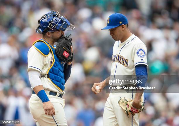 Catcher Mike Zunino of the Seattle Mariners and relief pitcher Edwin Diaz of the Seattle Mariners meet at the pitcher's mound during a game against...