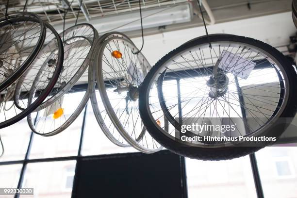 bicycle wheels hanging in bike workshop - hinterhaus stockfoto's en -beelden