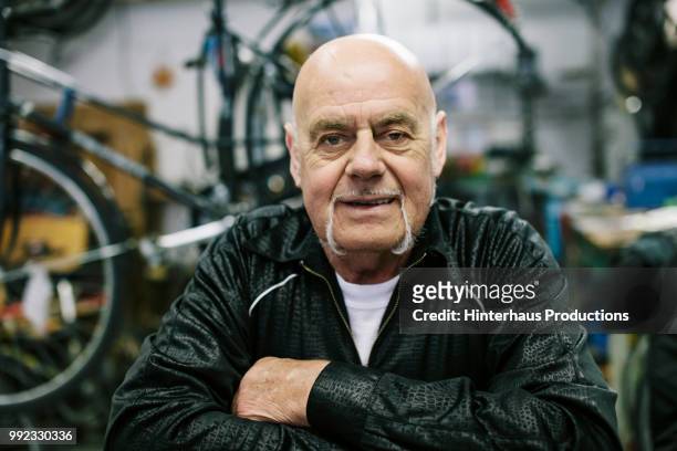 portrait of bicycle workshop owner - baldness stock-fotos und bilder