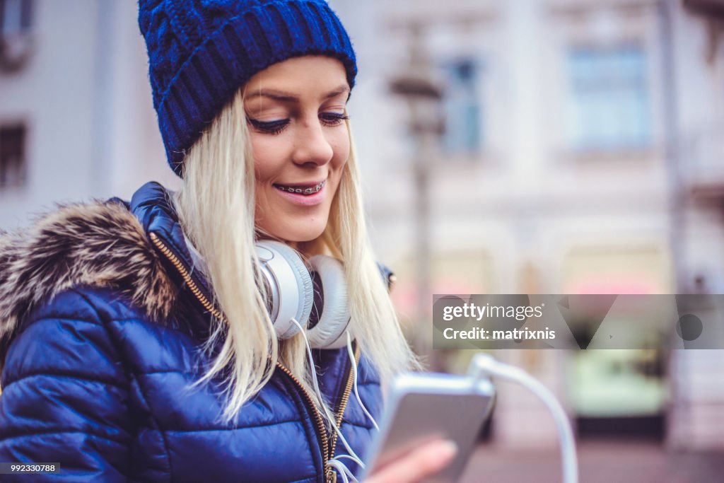 Elegante jonge vrouw luistert naar haar muziek in de stad