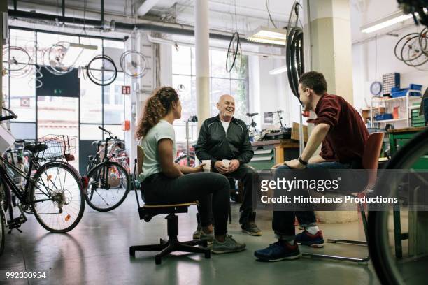 team of bike mechanics having meeting in workshop - bike shop stockfoto's en -beelden