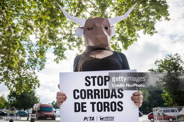 Activist against animal cruelty in bull fightings wears a paperboard bullhead mask before the San Fermin celebrations in Pamplona, Spain. Banner says...