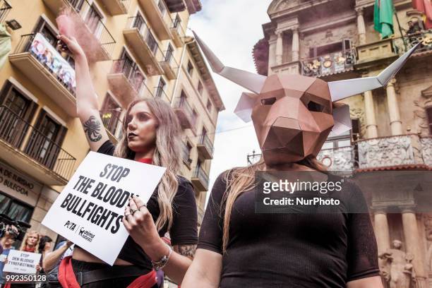 Activist against animal cruelty in bull fightings wears a paperboard bullhead mask before the San Fermin celebrations, Spain. Banner says &quot;stop...
