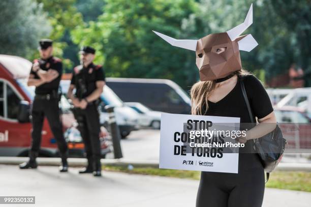 Activist against animal cruelty in bull fightings wears a paperboard bullhead mask near the local police before the San Fermin celebrations, Spain....