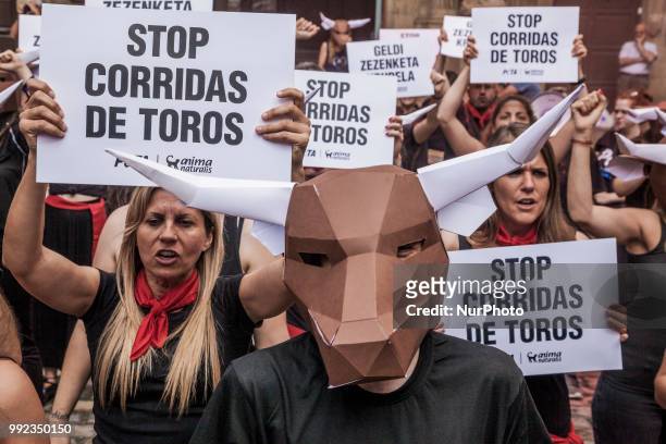 Protesters against animal cruelty in bull fightings before San Fermin celebrations in Pamplona, Spain. Banner says &quot;stop bullfightings&quot; and...