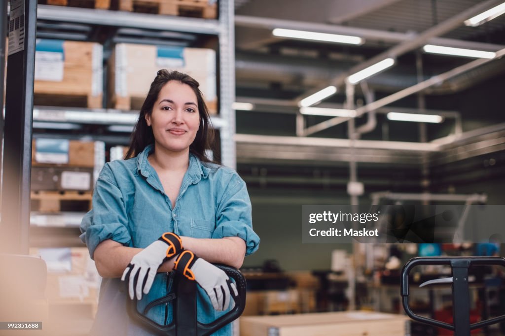 Portrait of young worker leaning on pallet jack at warehouse