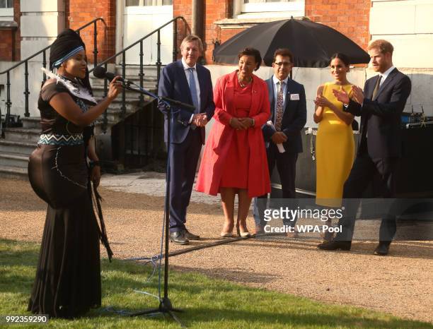Prince Harry, Duke of Sussex and Meghan, Duchess of Sussex accompanied by Commonwealth secretary general Baroness Scotland listen to music group...