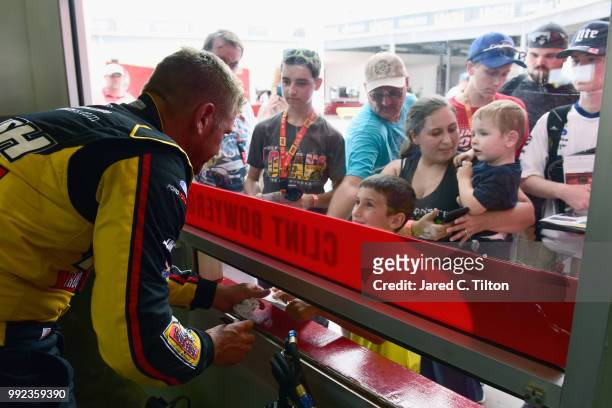 Clint Bowyer, driver of the Rush Truck Centers Ford, signs autographs during practice for the Monster Energy NASCAR Cup Series Coke Zero Sugar 400 at...
