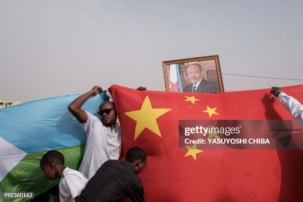 People hold Chinese and Djiboutian national flags as they wait for the arrival of Djibouti's President Ismail Omar Guelleh and before the launching...