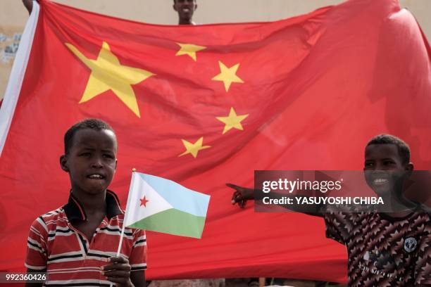 Boy holds Djiboutian national flag in front of Chinese national flag as he waits for Djibouti's President Ismail Omar Guellehas before the launching...