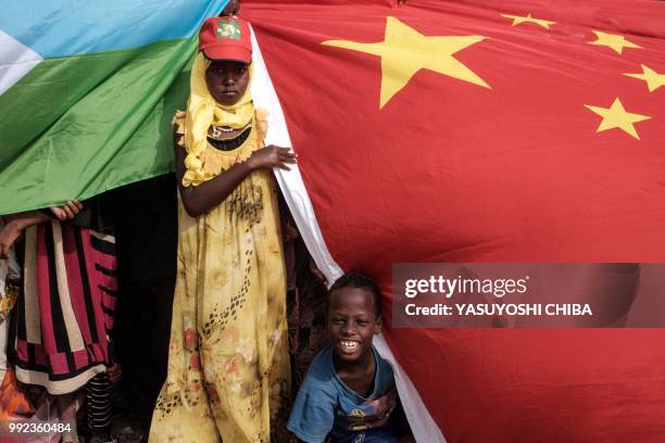 People hold Chinese and Djiboutian national flags as they wait for the arrival of Djibouti's President Ismail Omar Guellehas before the launching...