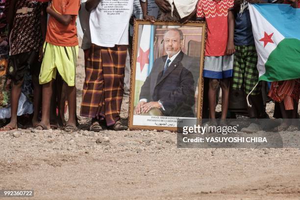 People hold the portrait of Djibouti's President Ismail Omar Guellehas as they wait for the arrival of the President before the launching ceremony of...