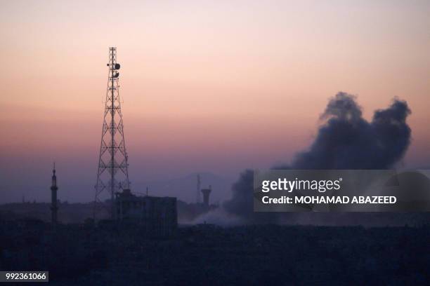 Smoke rises above rebel-held areas of the city of Daraa during reported airstrikes by Syrian regime forces on July 5, 2018. Waves of air strikes...