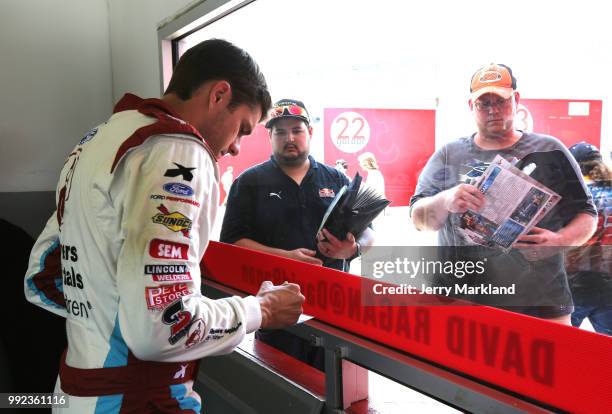David Ragan, driver of the Shriners Hospital For Children Ford, signs autographs during practice for the Monster Energy NASCAR Cup Series Coke Zero...