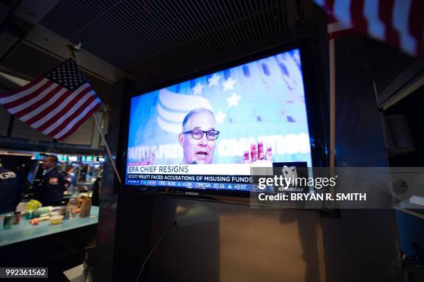 Television displays the news of Scott Pruitt's resignation as head of the EPA on the floor at the closing bell of the Dow Industrial Average at the...