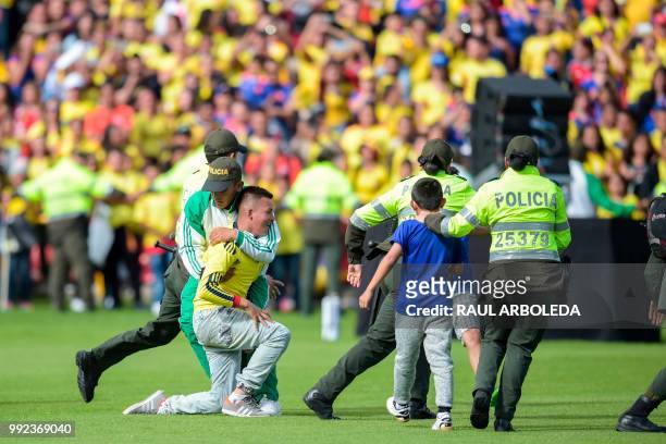 Fans are stopped by police as they enter the field during the welcoming ceremony of the Colombian national football team at El Campin stadium in...