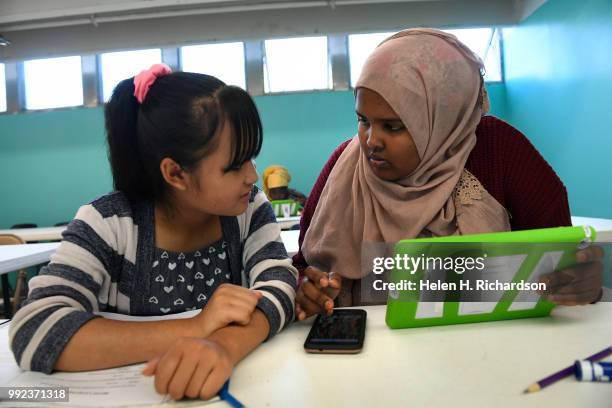 Volunteer youth mentor and counselor Farhiya Yussuf, right, helps Eh Ku left, work on making a Write Our Word ebook during summer day camp at the...
