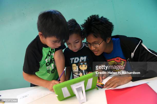 Volunteer youth counselor Ler Moo, right, helps campers Pedro left, and Mateo middle, work on making a Write Our Word ebook during summer day camp at...