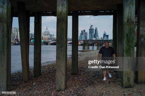 Man walks along the Thames at low tide on July 5, 2018 in London, England. A prolonged heatwave continues to grip much of the country, with no rain...