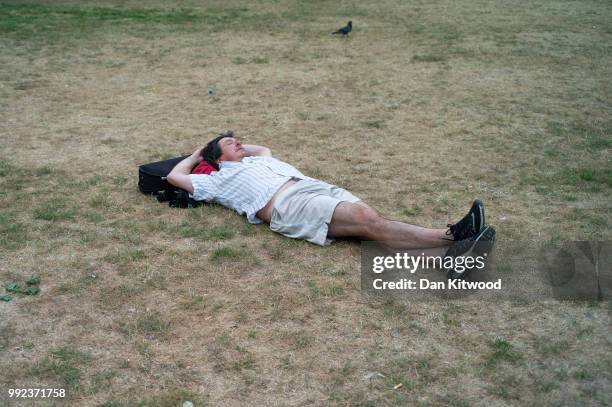 Man relaxes on dry grass in St James's Park on July 5, 2018 in London, England. A prolonged heatwave continues to grip much of the country, with no...