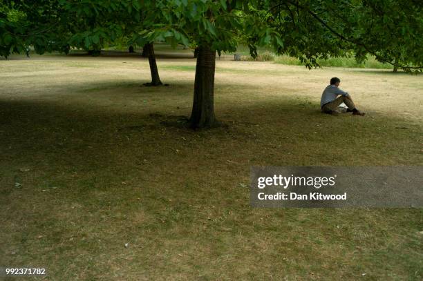 Man relaxes under a tree on dry grass in St James's Park on July 5, 2018 in London, England. A prolonged heatwave continues to grip much of the...