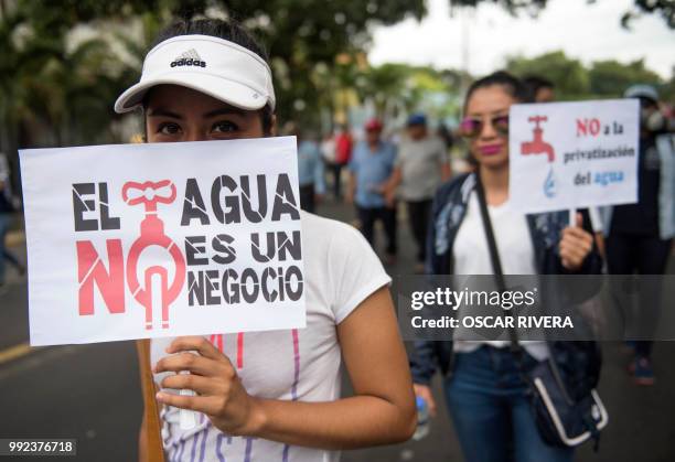 Woman holds a sign reading "Water is not a deal" as she takes part in a march against a water privatization bill under consideration of lawmakers in...