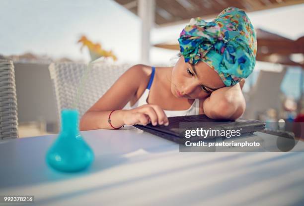 little girl is sitting sad with her laptop on the beach cafe - coastal deprivation stock pictures, royalty-free photos & images