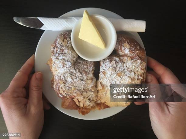 hands if a woman serving almond croissant-on a table in a cafe - rafael ben ari fotografías e imágenes de stock