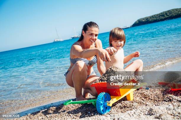 mother and son playing with toys at beach - dexters stock pictures, royalty-free photos & images