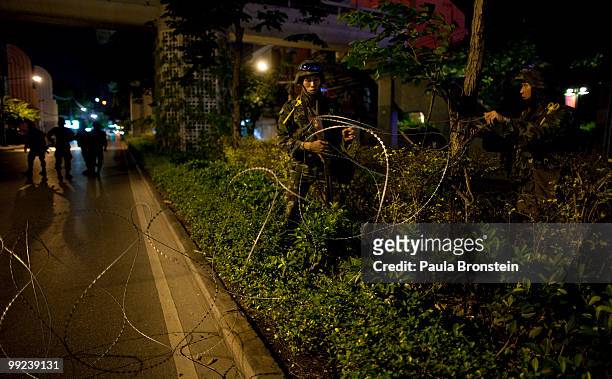 Thai soldiers unroll razor wire to block Silom Road on May 13, 2010 in central Bangkok, Thailand. The Black Shirt Guards are used as security forces...