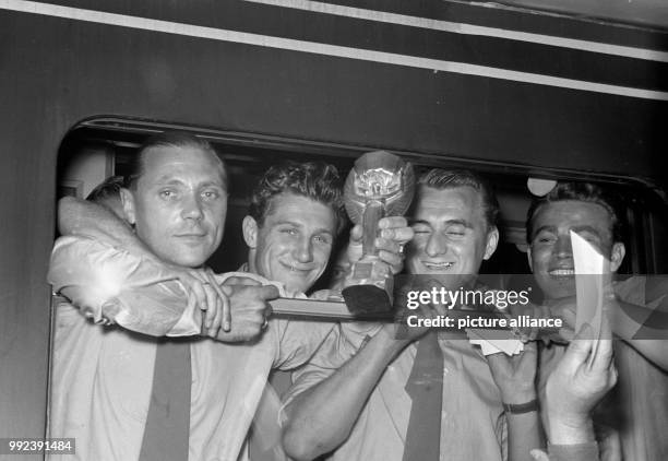 The players Max Morlock , Hans Schaefer, Jupp Posipal, Hans Bauer of the German national soccer team show the Jules-Rimet-Cup at the train window at...