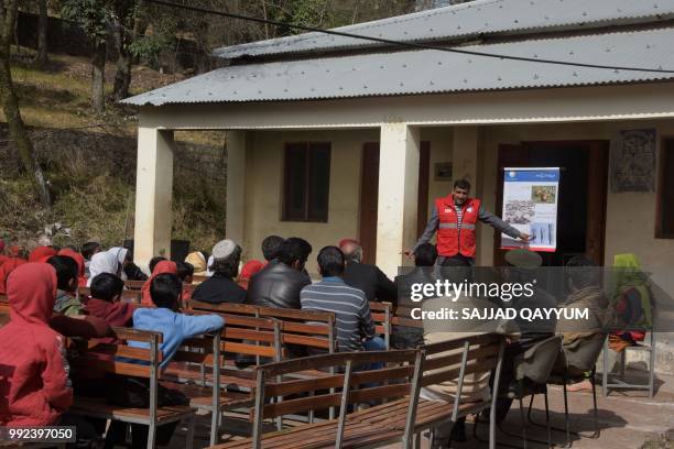 This picture taken on February 22, 2018 shows an official of the Pakistan Red Crescent Society leading an awareness campaign for landmines to local...