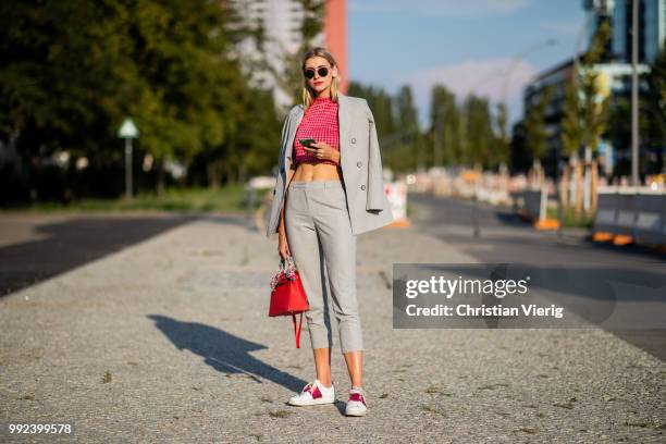 Kimyana Hachmann wearing grey cropped pants, red Hermes bag, grey jacket, cropped top is seen outside Dawid Tomaszewski during the Berlin Fashion...
