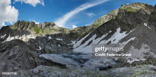 partly frozen upper paione lake (lago del paione superiore), bognanco valley - lepontinische alpen stock-fotos und bilder