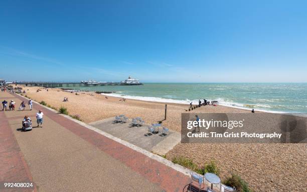 tourists on the promenade and beach at eastbourne, east sussex - eastbourne pier photos et images de collection